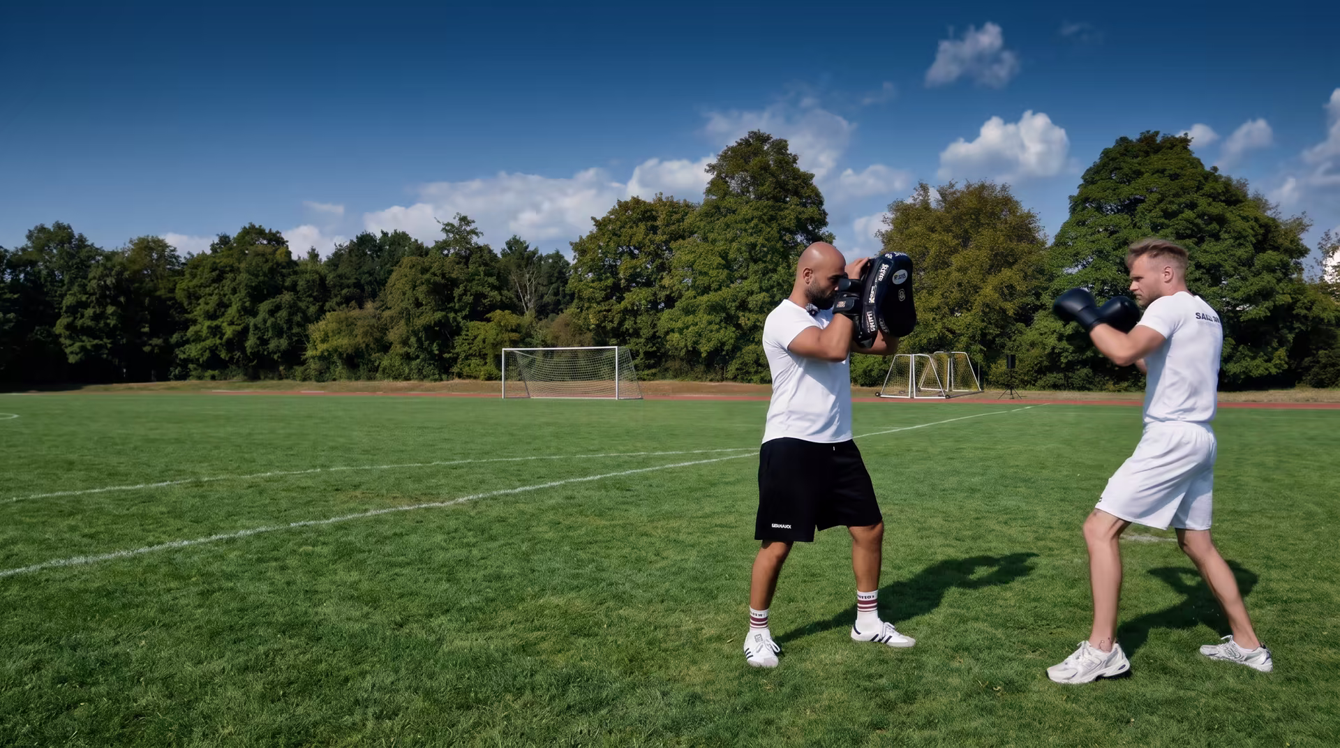 Coach Salim Lee hält die Pratzen, ein Sportler schlägt eine Gerade, Sportplatz in Reutlingen